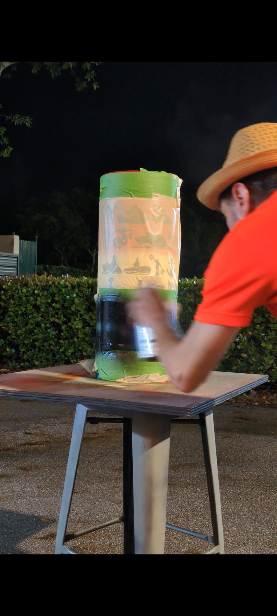 The artist painting a taped-off beer keg at night